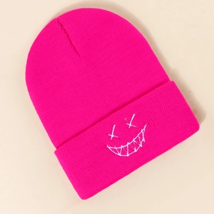 Detailed close-up of fuchsia knit beanie with white embroidered edgy face patch