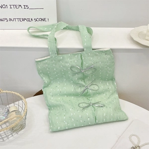 Detail of mint green lace tote bag featuring triple silver bows and sequined embroidery