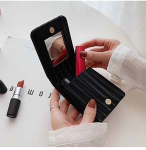 Portable black quilted leather lipstick case with built-in mirror held by hand