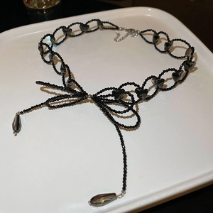 Close-up of black beaded bow necklace with elegant crystal teardrop pendants