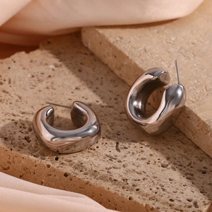 Macro shot of silver chunky hoop earrings with high-polish finish on stone and silk