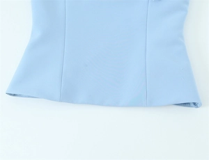 Detailed view of the hem stitching and light blue fabric texture of the bow top