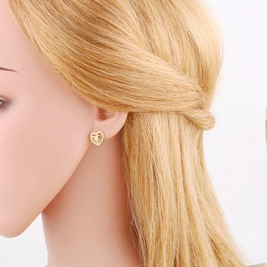 Close-up of golden heart stud earrings with zircon crystals on a gold hair model