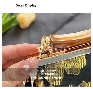 Macro shot of 3D gold flower embroidery on a black Qipao bag with amber resin handle