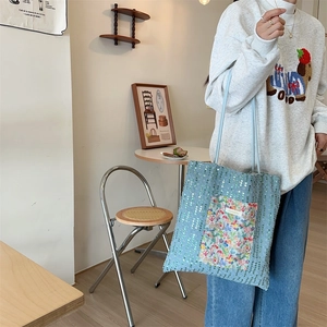 Detail of light blue sequin tote bag with colorful floral pocket and slim shoulder straps