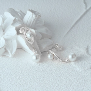 Detailed macro of S925 silver pearl drop earrings with elegant white stone accents