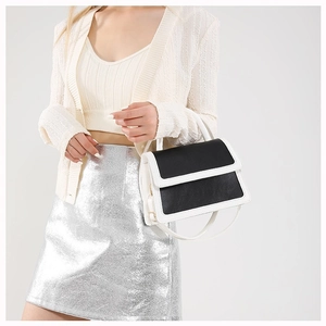 Modern black and white contrast top-handle crossbody bag held by model in knitwear
