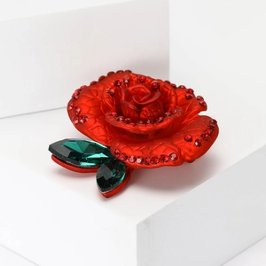 Elegant red enamel rose brooch with green crystal leaves on a modern geometric base