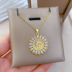 Close-up of golden Virgin Mary pendant with sparkling crystals on a thin link chain