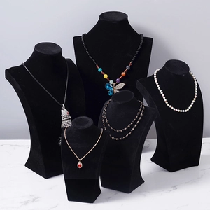 Five black velvet bust displays in varying heights showcasing necklaces on marble