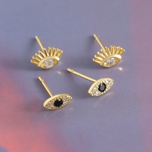 18k gold-plated evil eye stud earrings with sparkling crystals on a gradient background