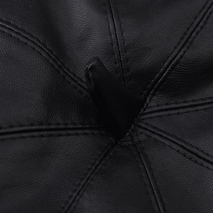 Close-up of black PU leather beret showing fine grain texture and radial stitching