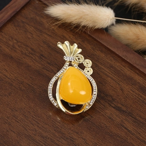 Macro view of gold money bag brooch featuring a yellow teardrop gem and sparkling crystals