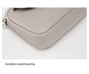 Detailed close-up of grey litchi grain leather texture and silver zipper of the bag