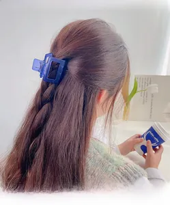 Close-up of a blue translucent rectangular hair claw clip worn by a model in a cozy setting