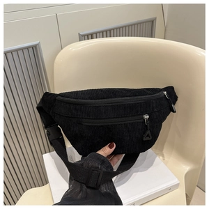 Detail of black corduroy belt bag featuring ribbed texture and adjustable strap