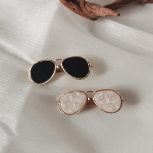 Sunglasses shaped hair clips in gold and black on white satin with elegant wood accent