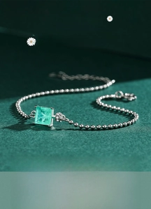 Close-up of S925 silver beaded bracelet with square emerald-cut green gemstone focal point