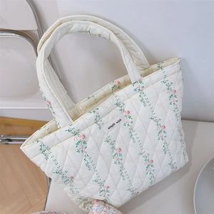 Detailed close-up of quilted floral cotton handbag featuring delicate stitching and label