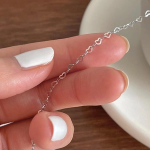Close-up of S925 sterling silver bracelet featuring delicate hollow heart-shaped links