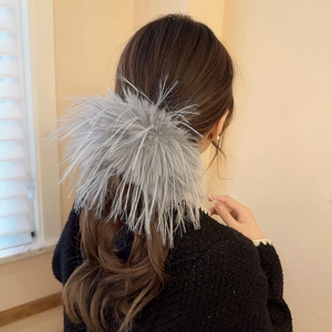 Vue arrière d'un mannequin portant une grande pince à cheveux grise en peluche et plumes