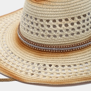 Close-up of hollow straw sun hat with rhinestone studded faux leather belt detail