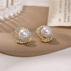 Macro shot of gold pearl earrings with a sparkling rhinestone halo on a soft background