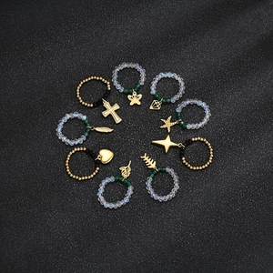 10-piece set of beaded elastic rings with diverse gold pendants on dark background