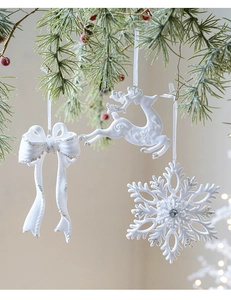 Close-up of white flocked Christmas ornaments with silver glitter on snowy pine branches