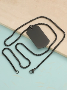 Close-up of a black titanium steel dog tag pendant with square box chain on marble surface