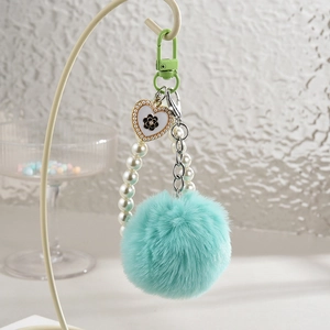 Détail du pompon vert menthe et chaîne de perles sur porte-clés pendentif cœur