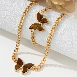 Detailed view of butterfly pendant necklace and ring set in gold with amber textures