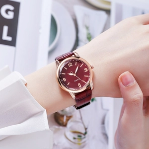 Detail of rose gold quartz watch with burgundy leather strap and crocodile texture