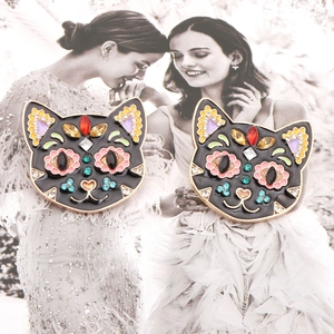 Detail of black enamel cat head earrings with vibrant colorful rhinestones on fashion art