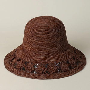 Close-up of handmade raffia sun hat featuring intricate crochet floral cutout details