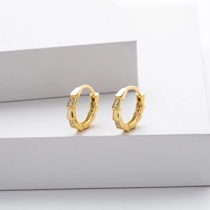 Minimalist gold bamboo hoop earrings with zircon stones on white geometric steps
