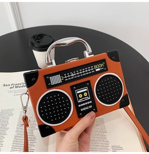 Detail of creative orange radio-shaped crossbody bag with silver handle and vintage print