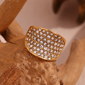Gros plan d'une bague large dorée sertie de cristaux brillants sur un fond de bois naturel