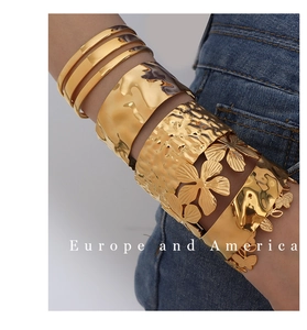 Detailed view of stackable gold-tone cuff bracelets featuring hammered texture and floral cutouts