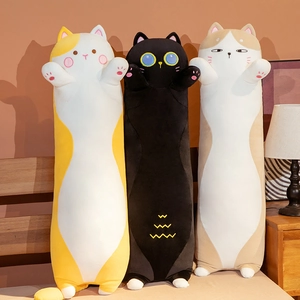 Three cute long cat plush bolsters in various colors displayed on a warm bed headboard