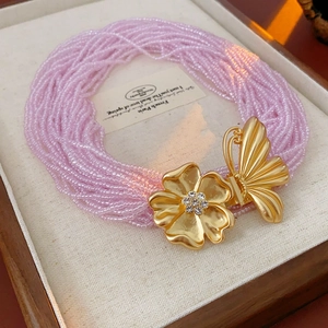 Detail of pink beaded multilayer necklace with gold butterfly and flower pendant