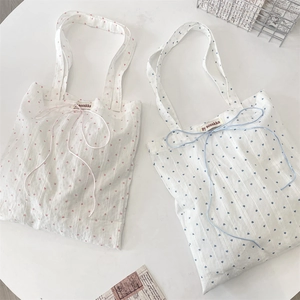 Detail of pink and blue heart-pattern canvas tote bags with delicate ribbon bow and woven label