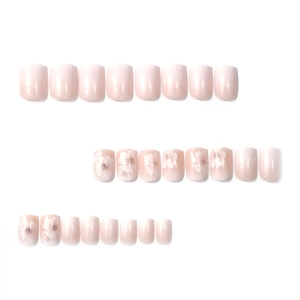 Short square press-on nails featuring light pink gradient and delicate white floral patterns