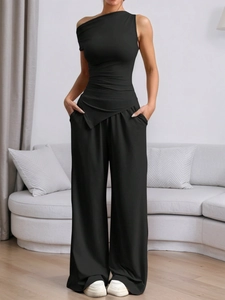 Detail of a chic black two-piece set featuring a one-shoulder crop top and wide-leg trousers