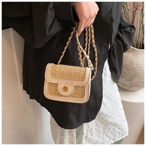Detail of mini straw crossbody bag featuring flower metal buckle and chain strap
