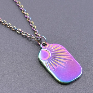 Macro detail of rainbow stainless steel pendant with solar sunburst engraving