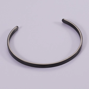 Macro detail of matte black stainless steel open cuff bracelet with brushed metal texture