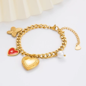 Detail of gold curb chain bracelet with red heart, butterfly, and pearl charms