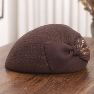 Detailed close-up of dark brown wool beret featuring mesh veil and beaded bow embroidery