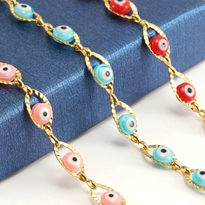 Close-up of golden evil eye bracelet with colorful enamel charms on blue jewelry box